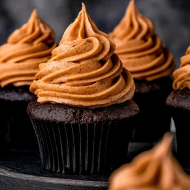Cozy chocolate pumpkin cupcakes topped with creamy frosting and sprinkled with chocolate shavings.
