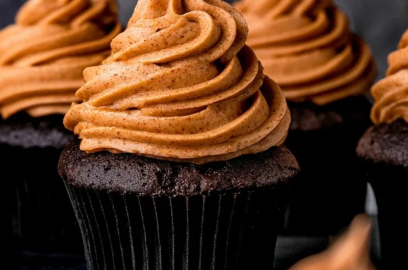 Cozy chocolate pumpkin cupcakes topped with creamy frosting and sprinkled with chocolate shavings.