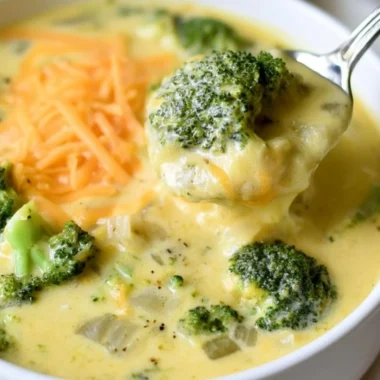 Bowl of cozy keto broccoli cheese soup garnished with cheese and herbs