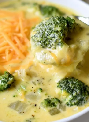 Bowl of cozy keto broccoli cheese soup garnished with cheese and herbs