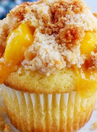 Homemade peach cobbler muffins with crumble topping on a rustic table