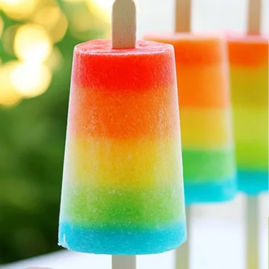 Colorful homemade rainbow popsicles on a wooden stick