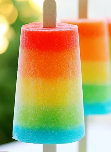 Colorful homemade rainbow popsicles on a wooden stick