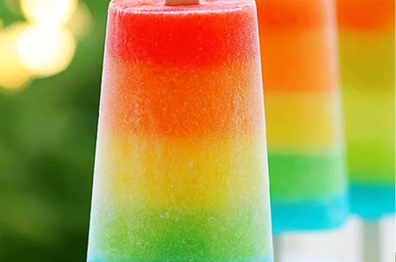 Colorful homemade rainbow popsicles on a wooden stick