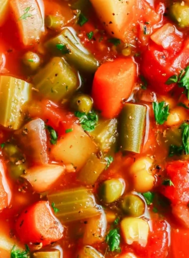 Bowl of hearty vegetable soup with fresh vegetables and herbs