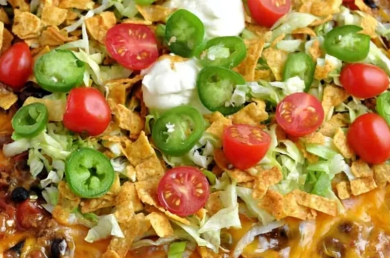 Walking Taco Casserole topped with cheese, lettuce, and taco toppings in a baking dish
