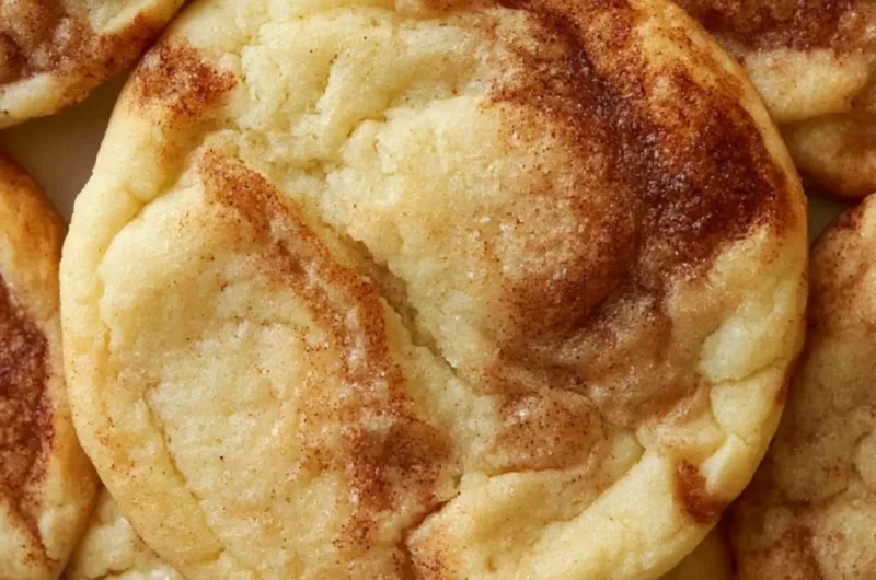 Soft and chewy cinnamon roll cookies on a baking tray, topped with cinnamon sugar.